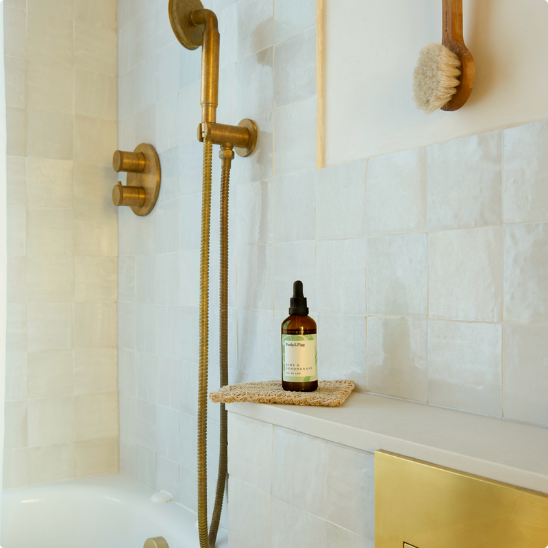 Oh! de Loo bottle on a shelf in a bathroom with white tiles and beautiful brass fittings